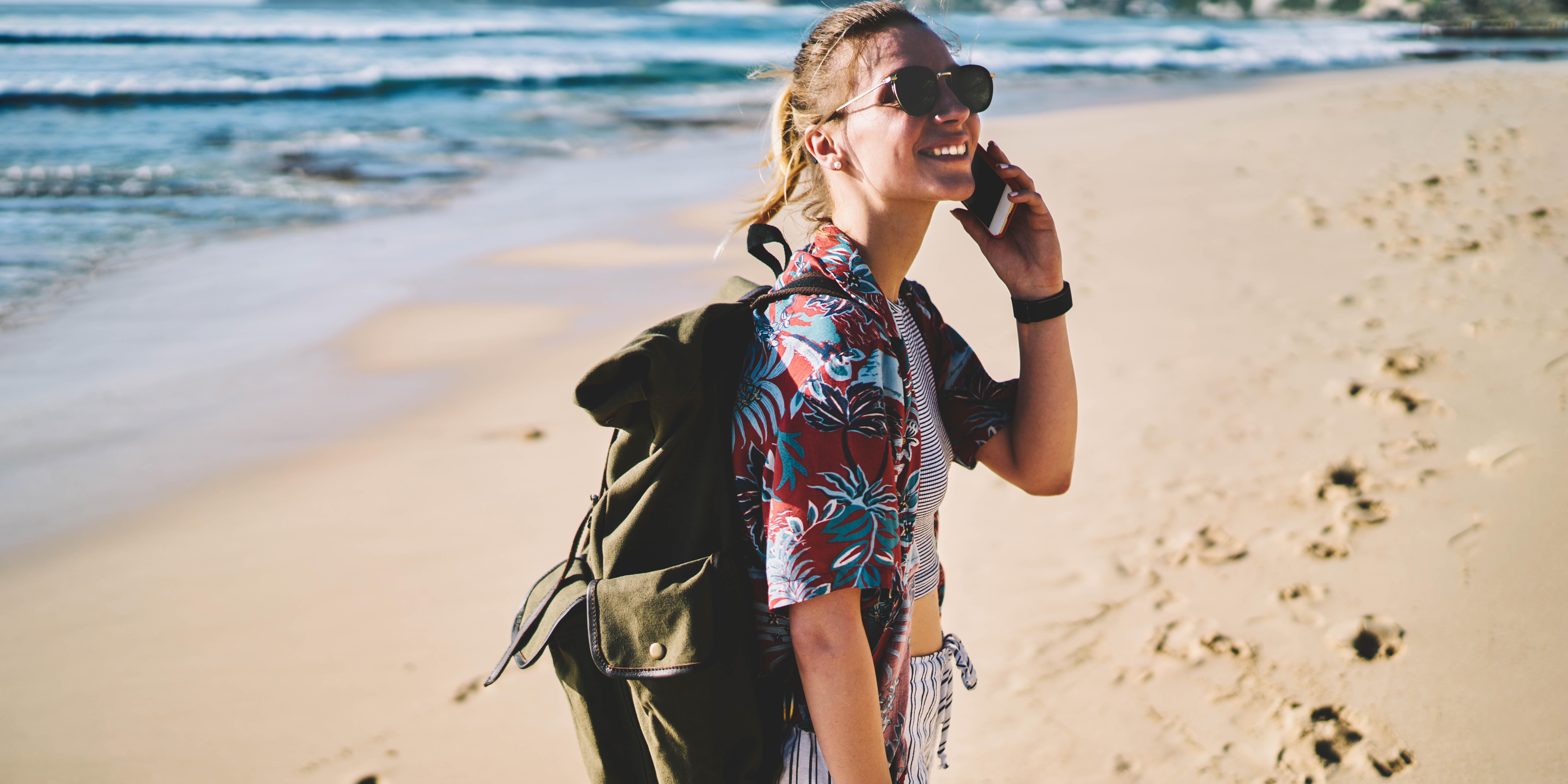 bilde av jente på stranda med mobil og ryggsekk